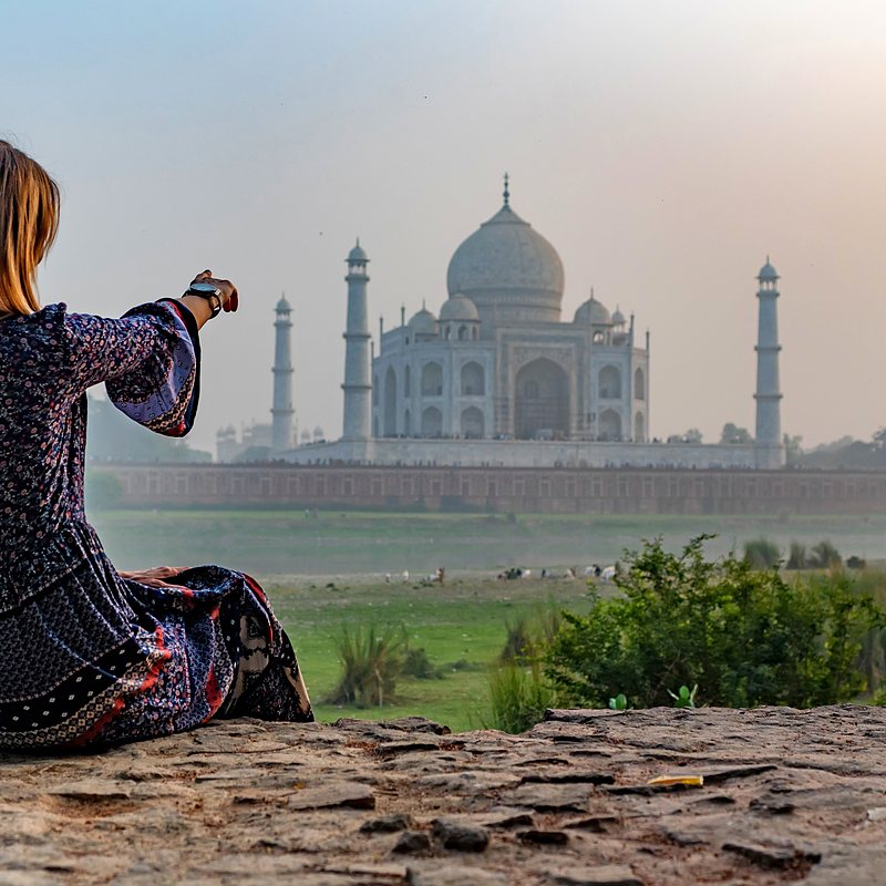 A traveler framing the Taj Mahal from the lawns